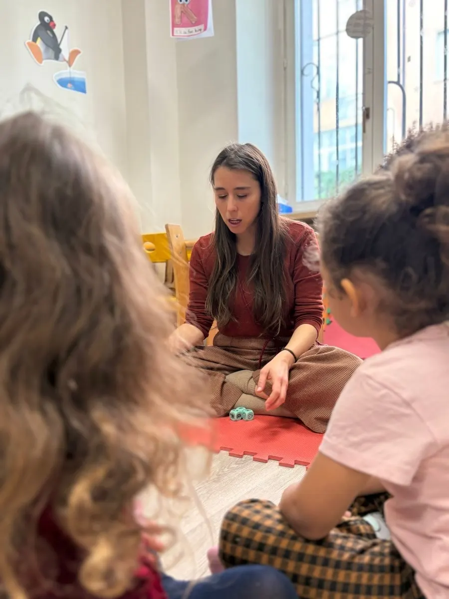 Susie seduta a terra insieme a un gruppo di bambini durante un'attività