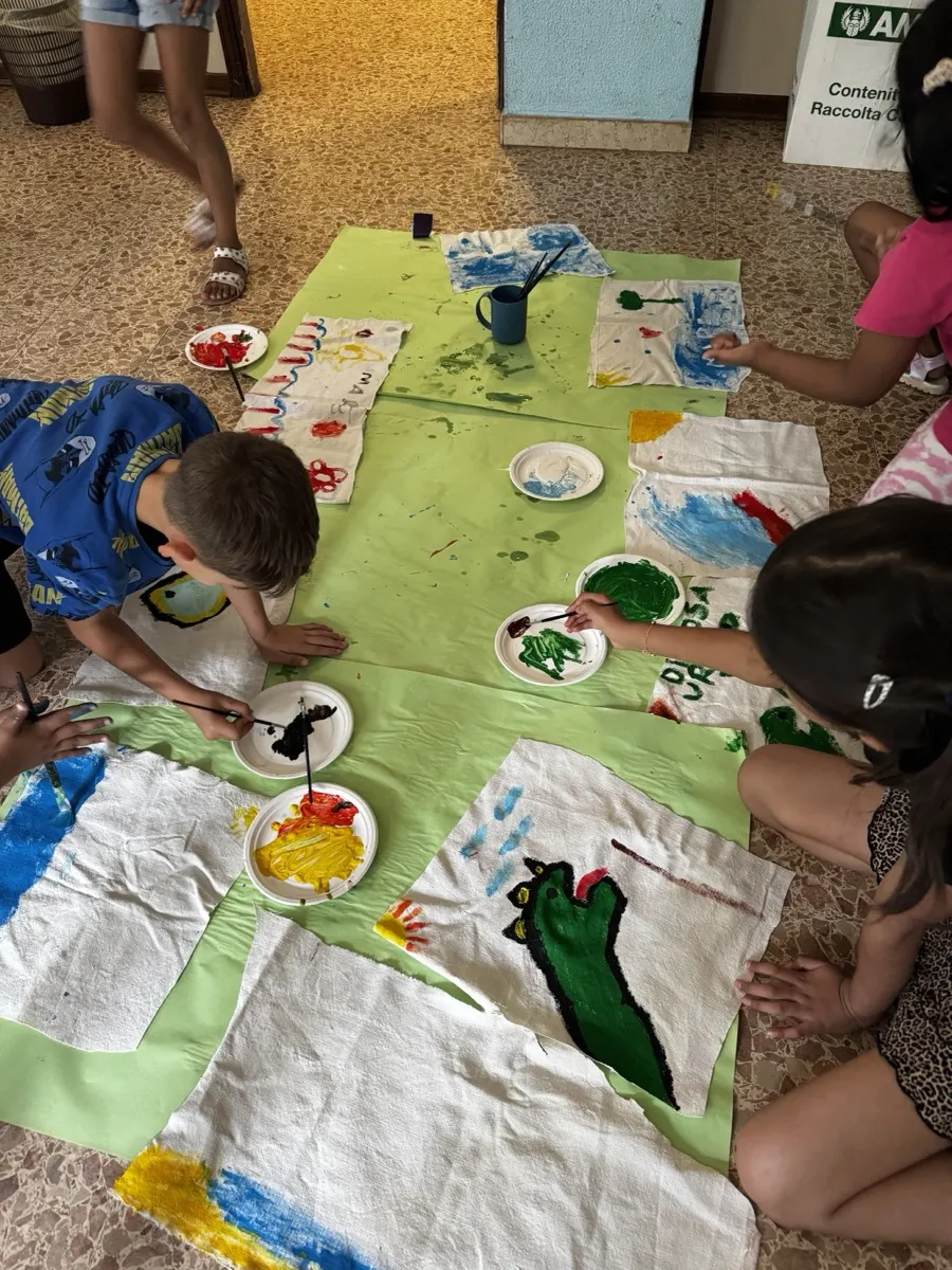 Bambini che dipingono su teli stesi a terra durante un laboratorio creativo