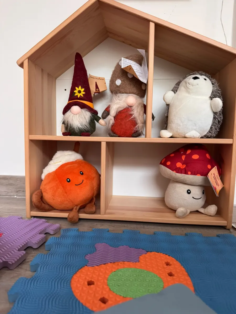 Libreria a forma di casetta con peluche di gnomi, funghi e un riccio