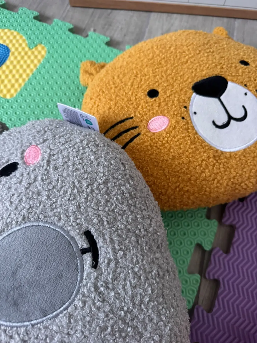 Cuscini morbidi a forma di animali sul tappeto puzzle colorato